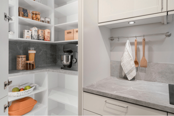 Well-organized pantry featuring shelves with food items, a stand mixer, and a countertop displaying kitchen tools, enhancing kitchen efficiency.