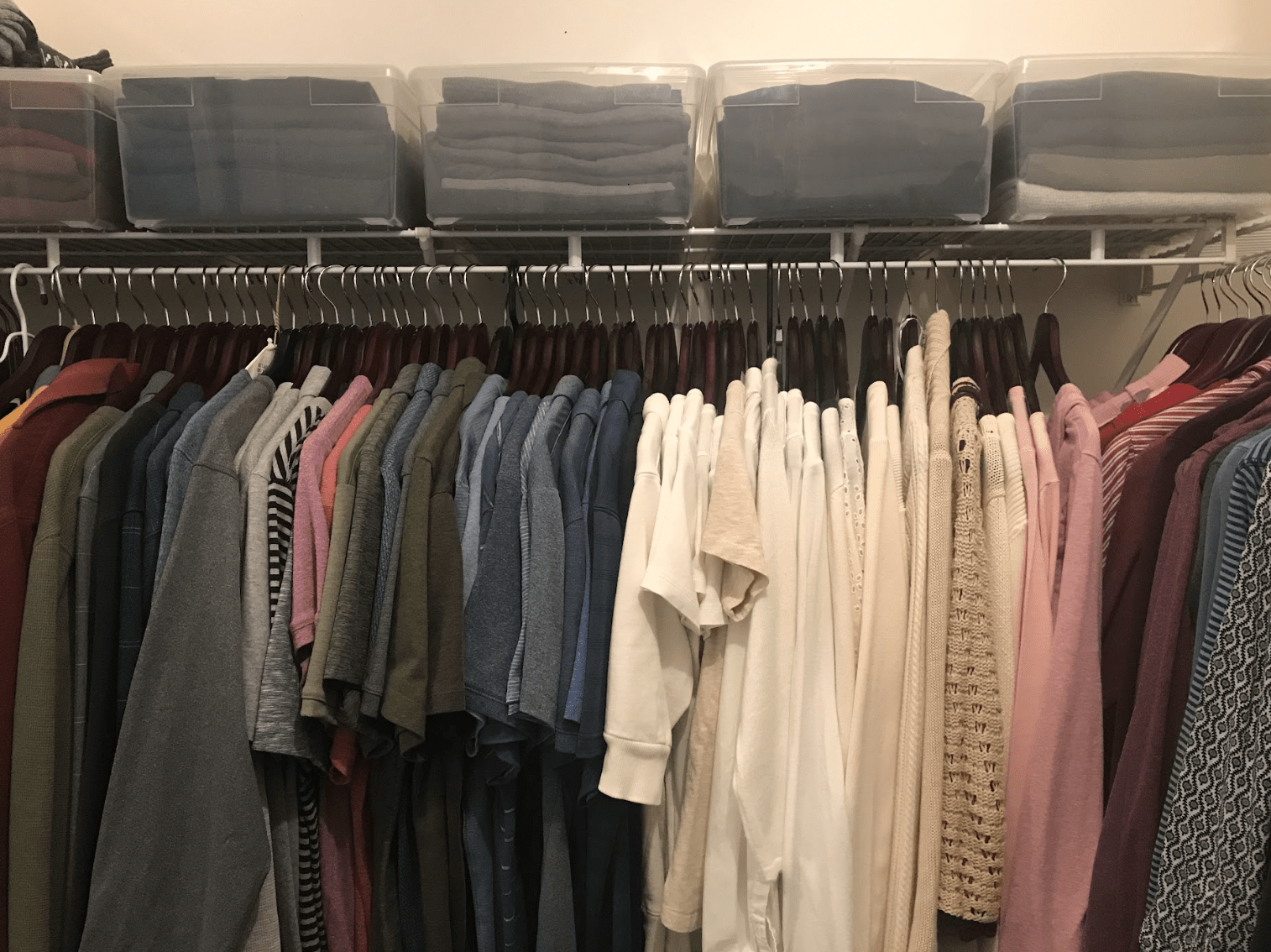 Organized closet showcasing a variety of shirts in different colors, with stacked storage bins above containing folded clothes.