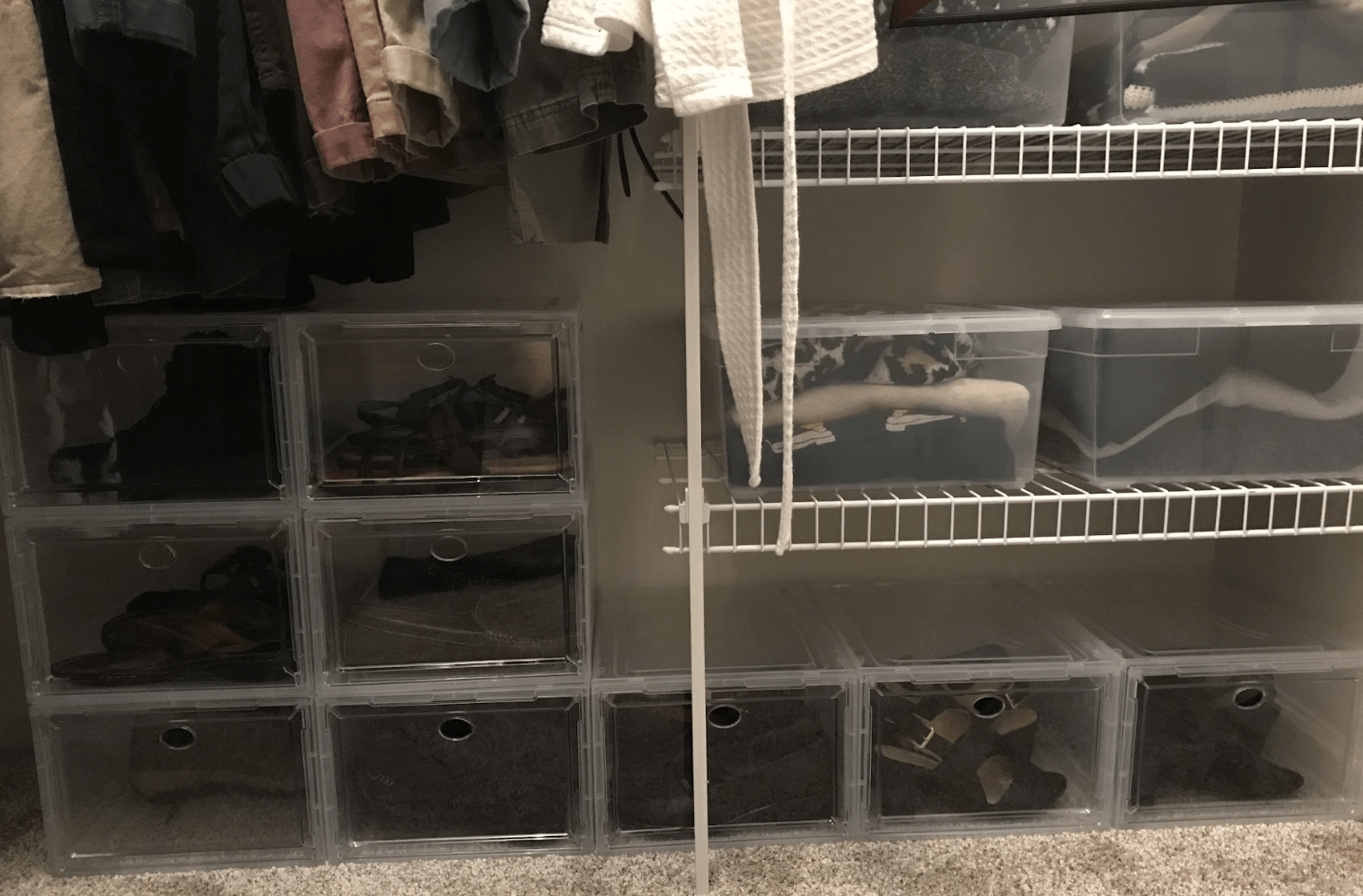 Organized closet space featuring clear storage bins for shoes and clothes on shelves, enhancing visibility and accessibility of items.